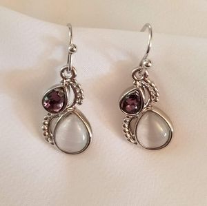 Earrings with moonstone and amethyst settings on silver colored metal.